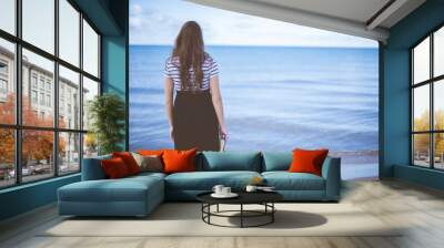 Female standing on beach shore while holding the bible with blurred background shot from behind Wall mural