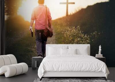 Male holding the bible walking up to the hill towards the cross with a blurred background Wall mural