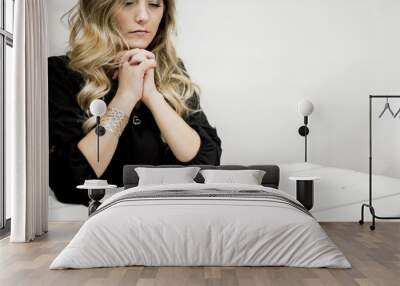 Woman praying in front of the bible on a table under the lights Wall mural