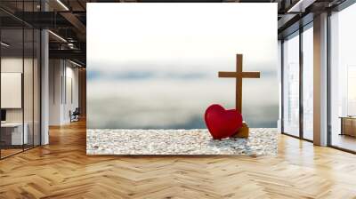 Wooden  Christian cross and red heart against morning light on sea. Wall mural