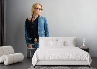 Beautiful stylish blonde model in jeans suit posing in studio Wall mural