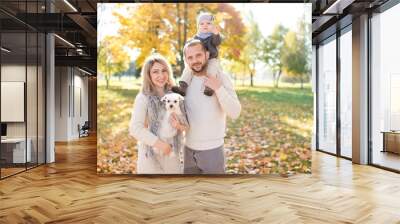 Happy family with their baby outdoor portrait. Father holding his little boy on shoulders. Wall mural