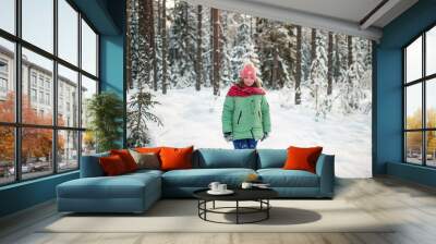 Portrait of plump funny girl in winter clothes posing for camera in snowy forest. Wall mural