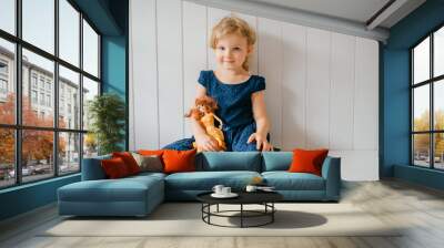 Trubschachen, Switzerland - December 16, 2019: Portrait of cute little girl holds her lovely barbie, sits in bright baby room and smiles Wall mural