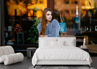 Young odd beautiful model girl with sensual pensive face posing for camera outdoor in front of shop showcase with abstract reflections in morning. Amazing teenager female with blue eyes mood portrait. Wall mural