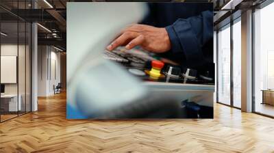 Close-up of African production engineer's hand with safety wear operating CNC machine in the factory. A male factory worker is programming and adjusting industrial machine to control the production. Wall mural