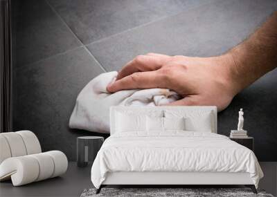 Man's hand wipes clean rag across freshly installed vinyl flooring tiles. Wall mural