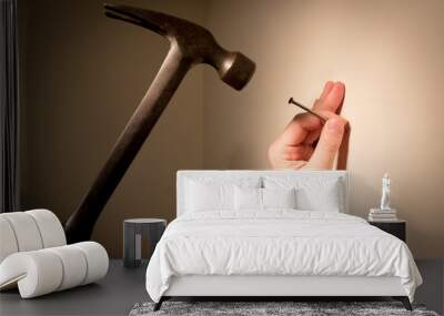 Man's hands prepare to hit a nail with a hammer; on blank wall for picture hanging. Wall mural