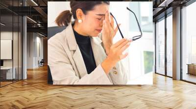 Asian businesswomen feel stressed, tired from work, migraine headaches from hard work while working at the office. Wall mural