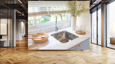 Clean new sink in stylish kitchen interior by the window. Wooden utensils and ceramic vase with flower on kitchen counter. Wall mural