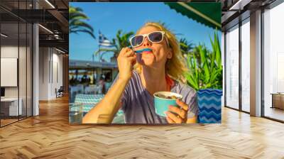 Healthy Mediterranean diet. Blonde caucasian female eating healthy food outdoor. Europe summer vacation. Lifestyle woman eating typical Yogurt Greek in Koroni, Peloponnese, Greece. Summer holidays. Wall mural