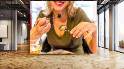 Smiling woman eating snails with herbs butter. Traditional French dish. Female enjoying in typical local street food in Latin Quarter, Paris, Europe.Travel lifestyle woman shows escargots of Bourgogne Wall mural