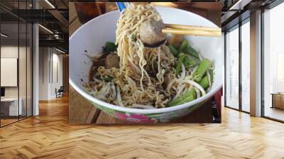 Focus on the spoon, chopsticks scooping instant noodles and meatballs in a bowl : delicious boat noodle recipe available in Thailand Wall mural