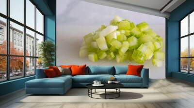 Green Celery Being Sliced on White Cutting Board With Chef's Knif and Wood Stand Wall mural