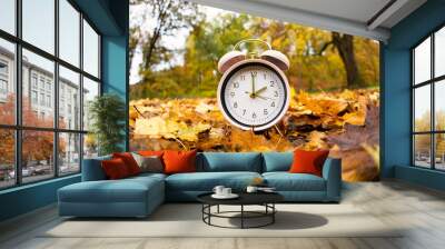 End of daylight saving time in fall, winter time changeover,  alarm clock with autumn foliage Wall mural