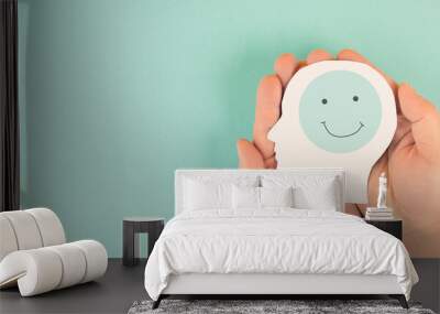 Holding a head with a happy smiling face in the hands, mental health concept, positive thinking, support and evaluation  Wall mural