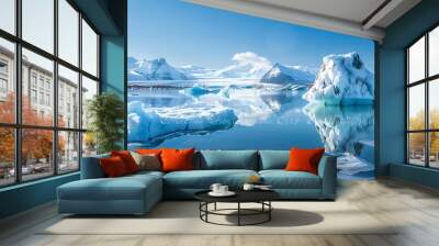 Serene view of the jokulsarlon glacier lagoon in iceland, featuring vivid blue icebergs against a backdrop of snowy mountains under a clear sky.  Wall mural