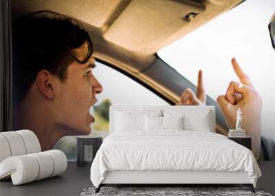 Young driver looks angry in his car while showing two middle fingers. Wall mural