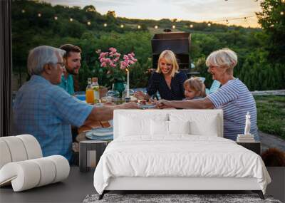 Affectionate family enjoying dinner during their get together in the backyard Wall mural