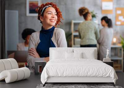 Attractive young Hispanic business woman looking on side while sitting in office. Wall mural