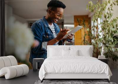 Black woman relaxing at home and using digital tablet Wall mural