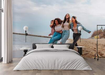 Four young women jumping together on beach Wall mural