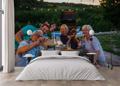 Happy senior man and his extended family taking selfie during dinner in the backyard Wall mural