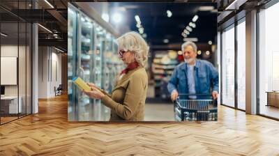 Senior couple choosing groceries in supermarket Wall mural