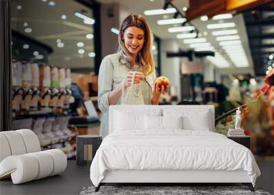 woman shops for produce in supermarket Wall mural