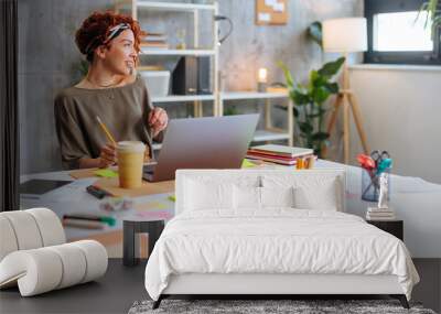 Young Hispanic business woman sitting by office desk looking to the side. Wall mural