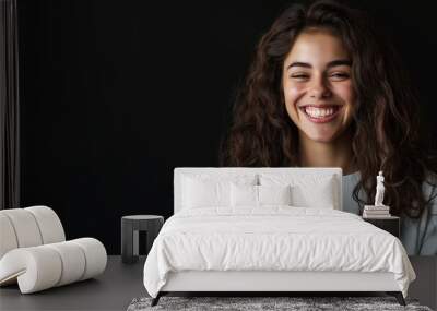 young smiling woman using mobile phone against black background Wall mural