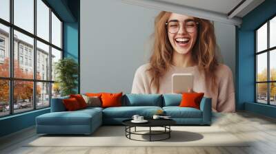 young smiling woman using mobile phone against gray background Wall mural