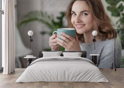 Woman holding a cup of coffee. Drink morning. A girl in a cozy house drinks a hot drink. Wall mural