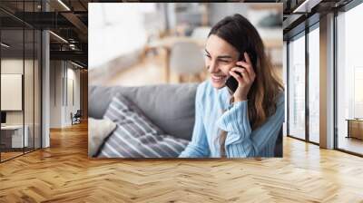 Attractive smiling woman talking on the phone at home. Wall mural