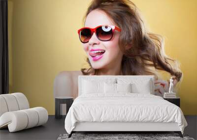 Attractive surprised young woman wearing sunglasses on gold back Wall mural