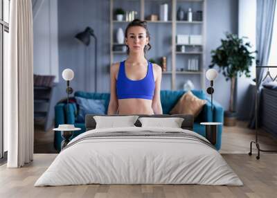 Beautiful woman woman in blue sportswear at home. Wall mural