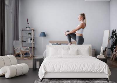 Full length portrait of attractive young woman working out at home, doing pilates exercise on mat. Wall mural