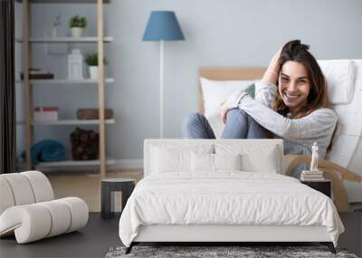 Happy woman resting comfortably sitting on modern chair in the living room at home. Wall mural