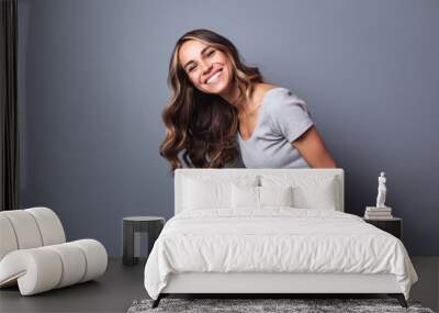 Laughing young woman standing against a gray wall. Wall mural