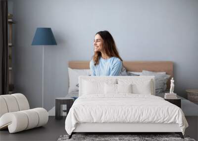 Relaxed smiling woman sitting on sofa at home. Wall mural