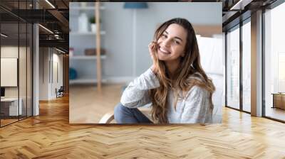 Smiling millennial girl sitting in a cozy chair at home. Wall mural