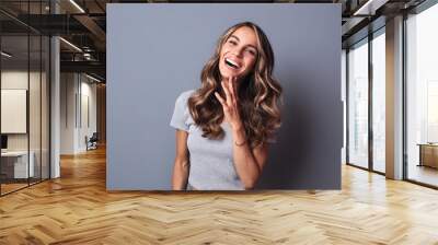 Smiling woman on grey wall background. Wall mural