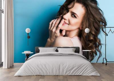 Smiling young woman on blue wall background. Wall mural