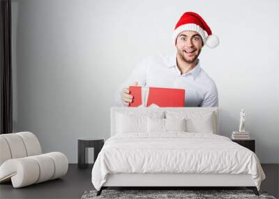 Surprised man in santa hat with gift box on white. Wall mural