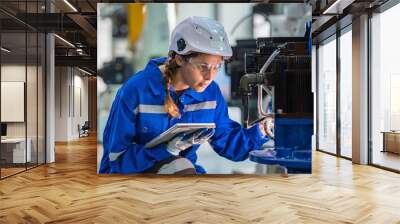 woman engineer in uniform helmet inspection check control heavy machine robot arm construction installation in industrial factory. technician worker check for repair maintenance electronic operation Wall mural