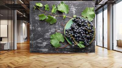 Black grapes in plate with vine plant on dark table top view. Sweet juicy grapes food on black concrete background flat lay with copy space. Wall mural