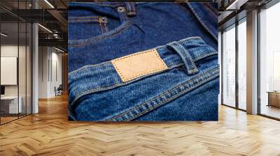 Blue denim jeans with emty label. Brown blank leather label tag on denim pants background. Blank mockup beige leather label. Close up Wall mural