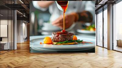 A chef is pouring sauce over a plate of food Wall mural