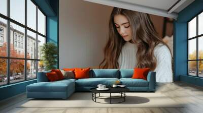 A teenage girl reading a book in a cozy indoor setting, with a soft, warm light illuminating the scene, conveying calm and concentration. Wall mural