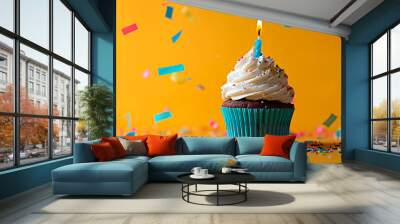 Cupcake with a lit candle and colorful confetti against a yellow background, perfect for a joyful and festive birthday celebration Wall mural